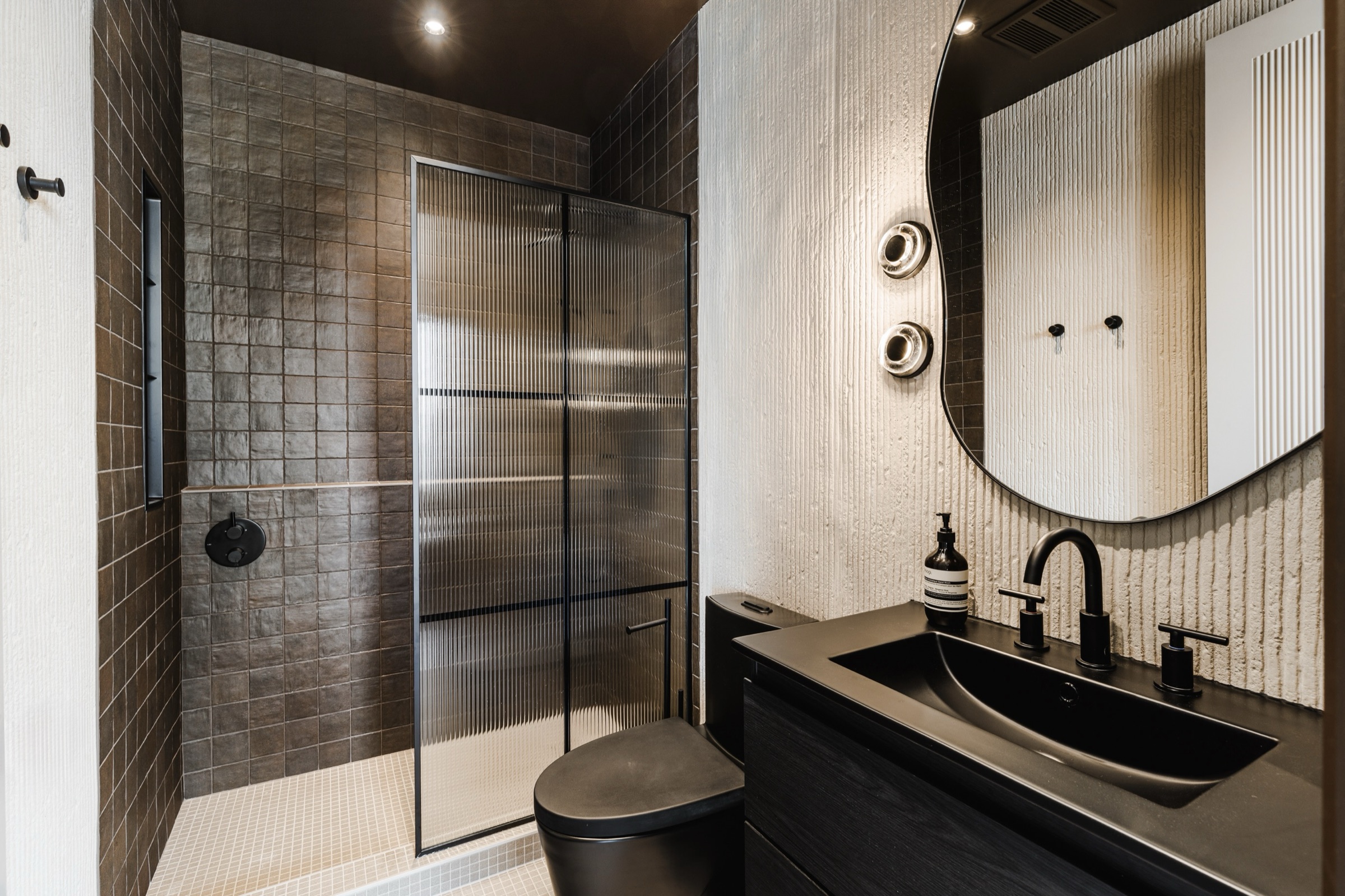 Salle de bain d'invités, finitions noires et dorées avec céramique italienne